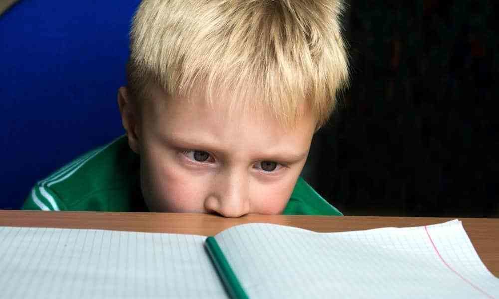 pediatrician screening for ADD and ADHD young blonde boy staring at notebook in concentration